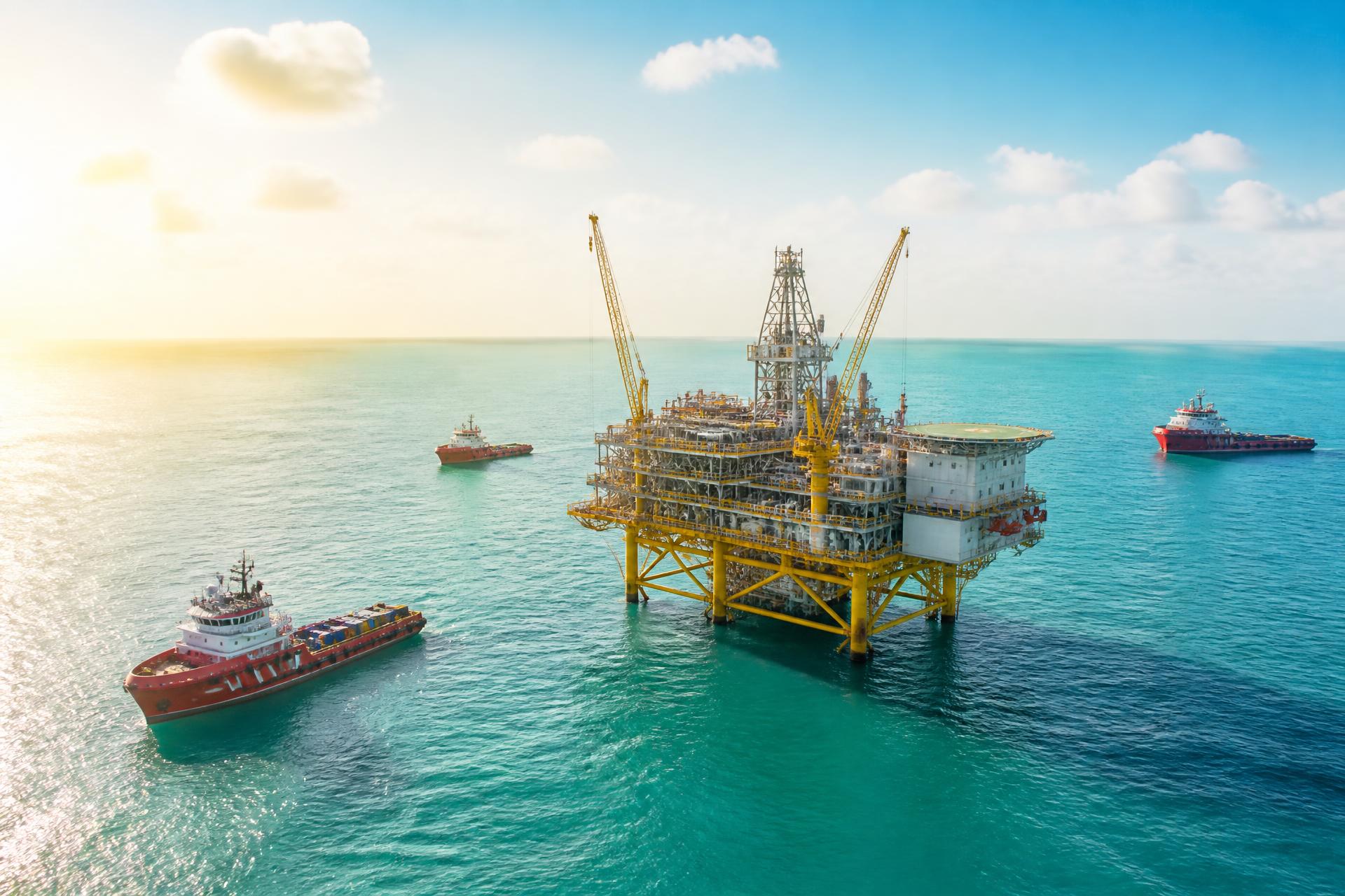 Offshore oil platform and support vessels at sunrise